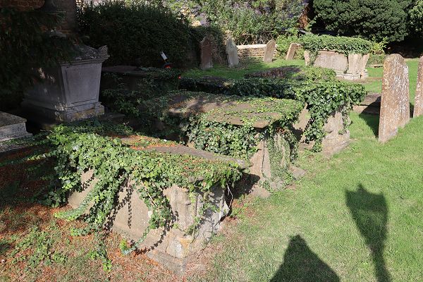 Three ivy-covered chest tombs