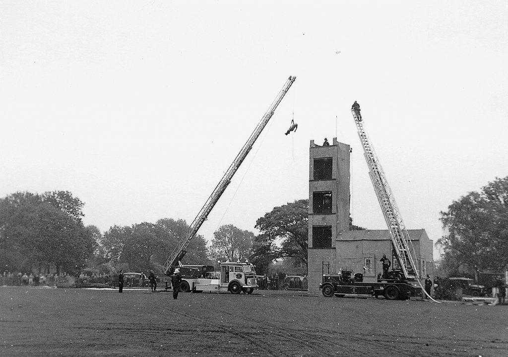 Two fire engines with extended ladders. Training tower in the background