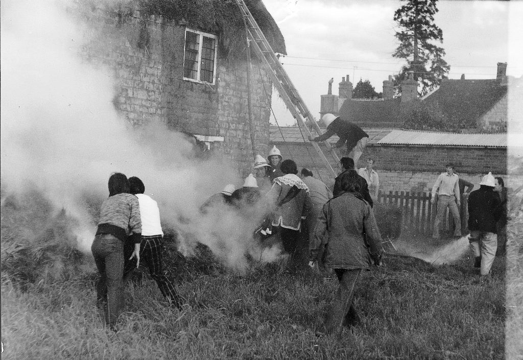 Fire brigade tackling thatched roof fire