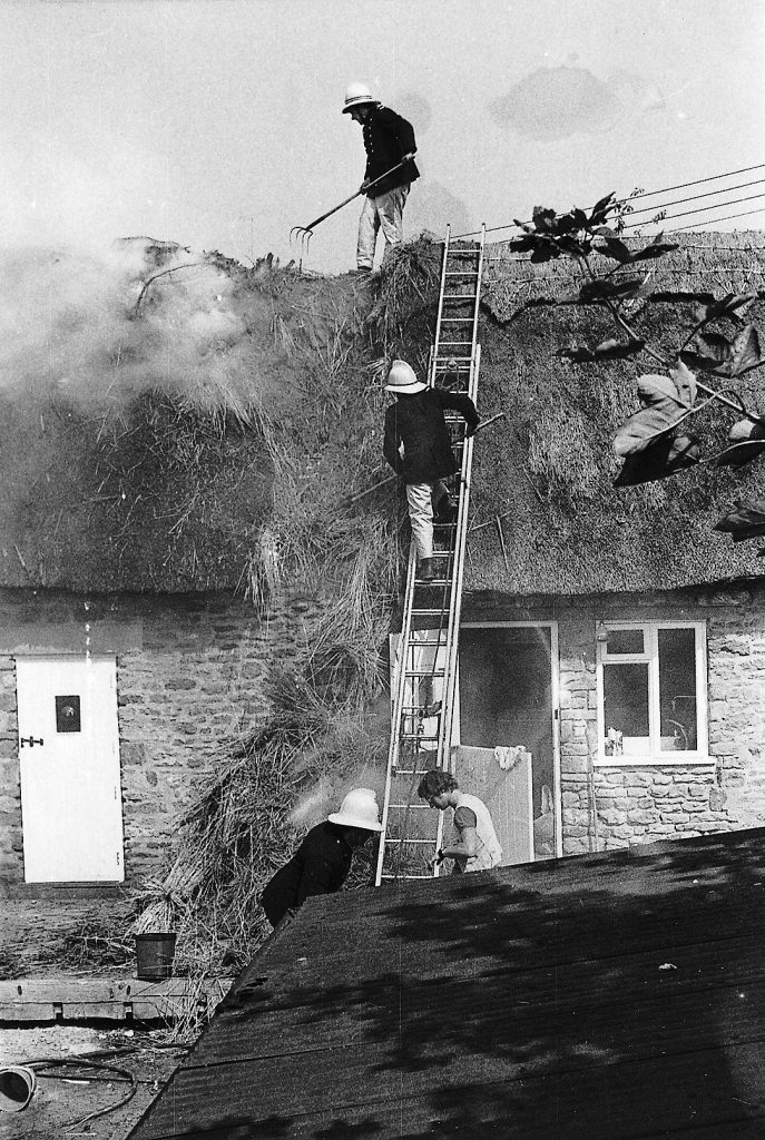 Firemen attending a thatch roof fire