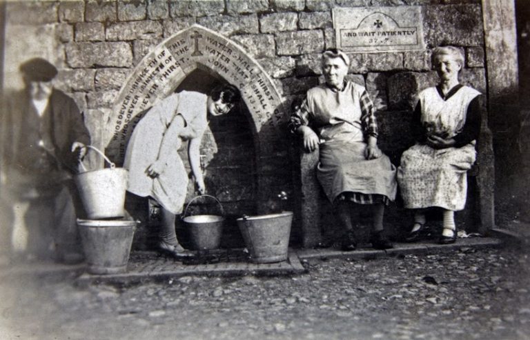 People collecting water in pails from a wellhead