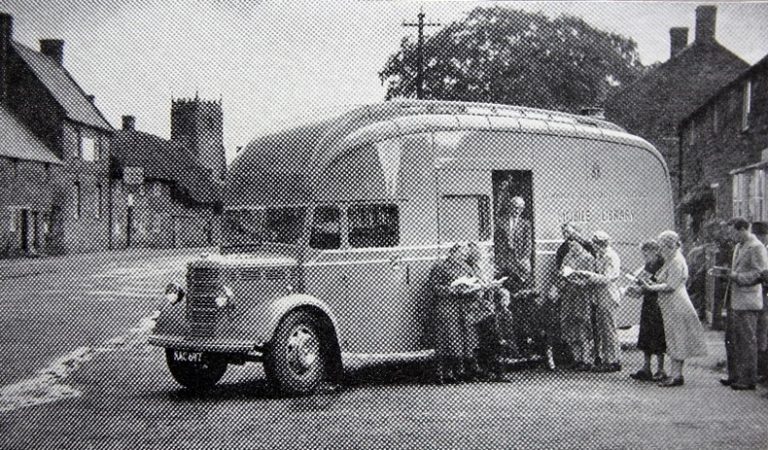 Vintage mobile library van with people waiting to board
