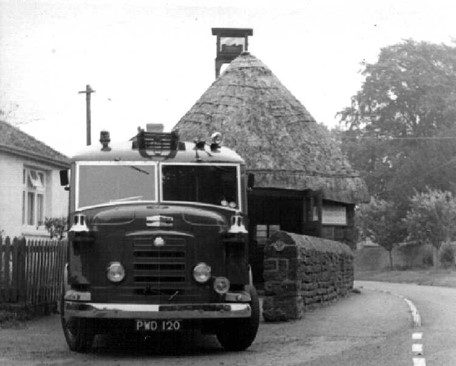 Fire engine parked in front of thatched building