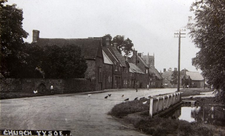 Village street with houses and a pond