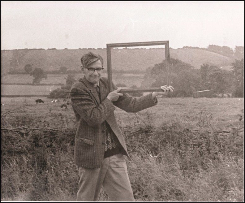 Man holding a frame against a hillside