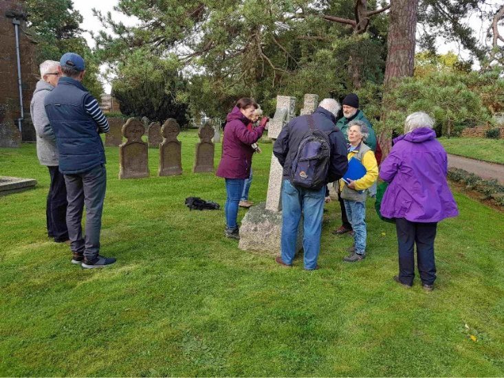 Group of people inspecting headstone composition