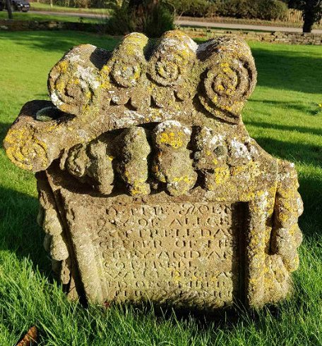 Ornately carved headstone, broken on the right
